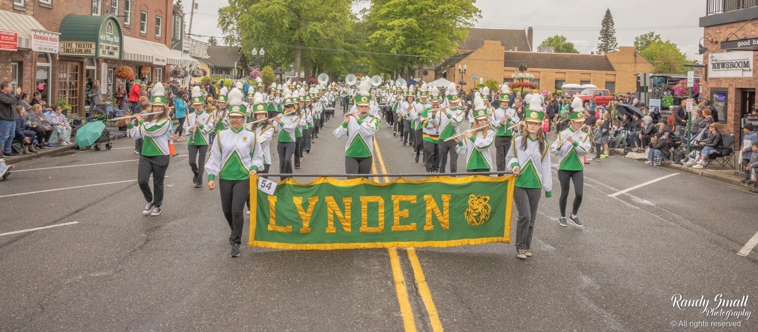 Marching band walking down a rainy street holding a 'Lynden' banner